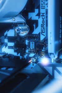 Detailed view of ASRock B550 motherboard circuitry with blue ambient lighting, showcasing modern technology.